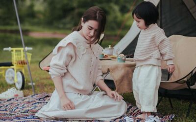 Deux enfants jouent sur un tapis à proximité d'une tente de camping beige en plein air