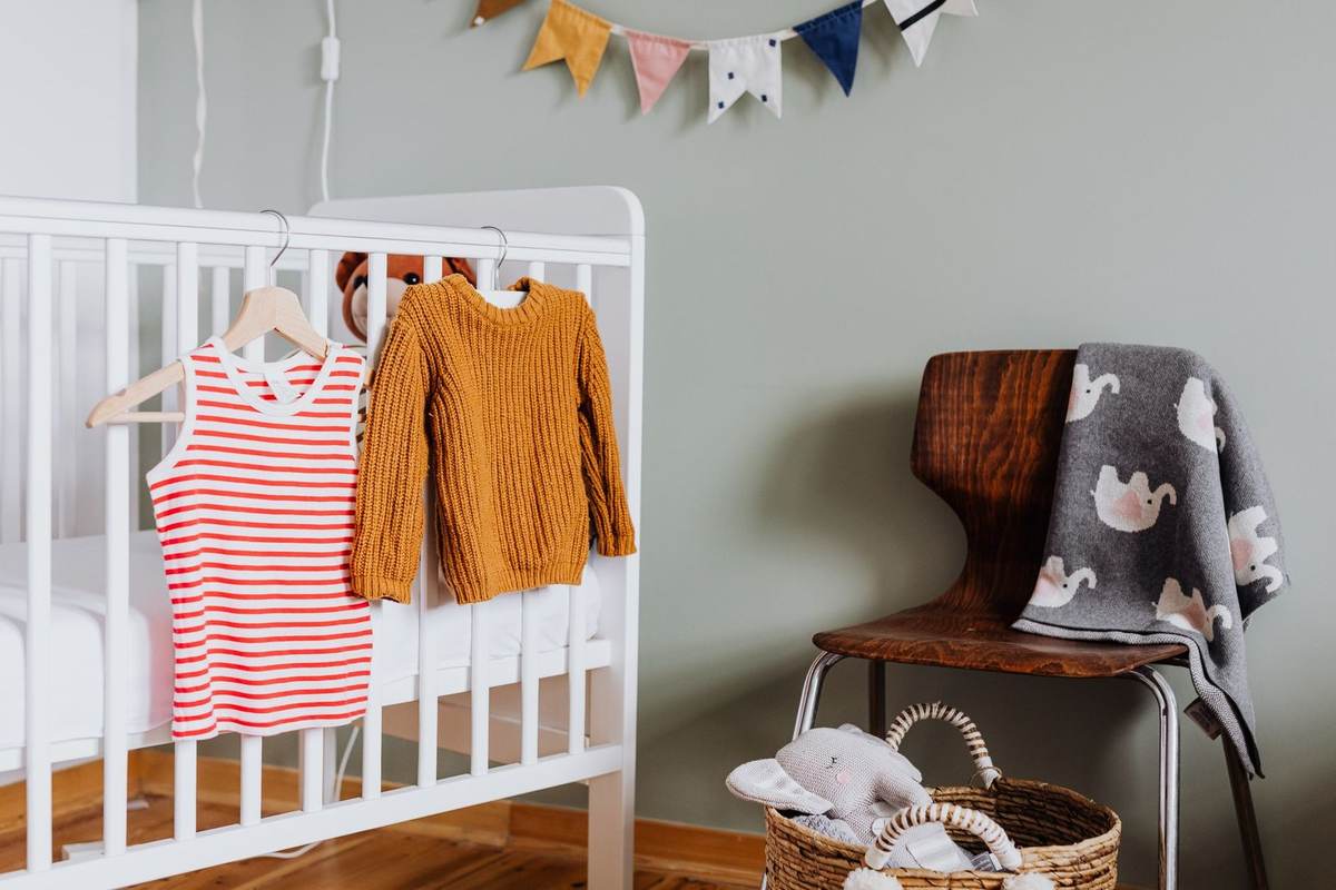 Berceau avec vêtements, panier de jouets, chaise avec couverture, bannières colorées