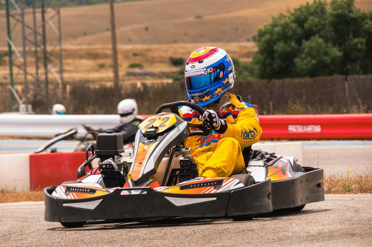 Un coureur en kart jaune avec casque coloré sur un circuit