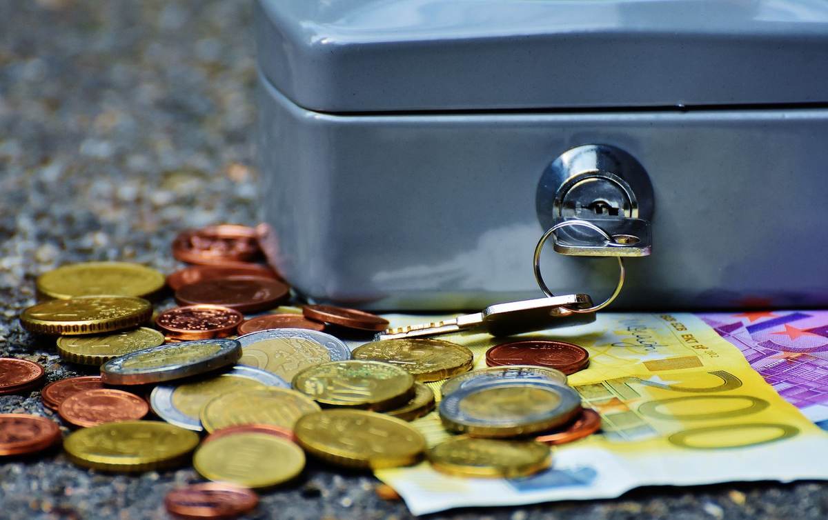 Pièces et billet sur gravier, boîte à clés avec clé en position ouverte