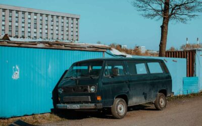 Van noir à côté d'un conteneur bleu sous un ciel clair
