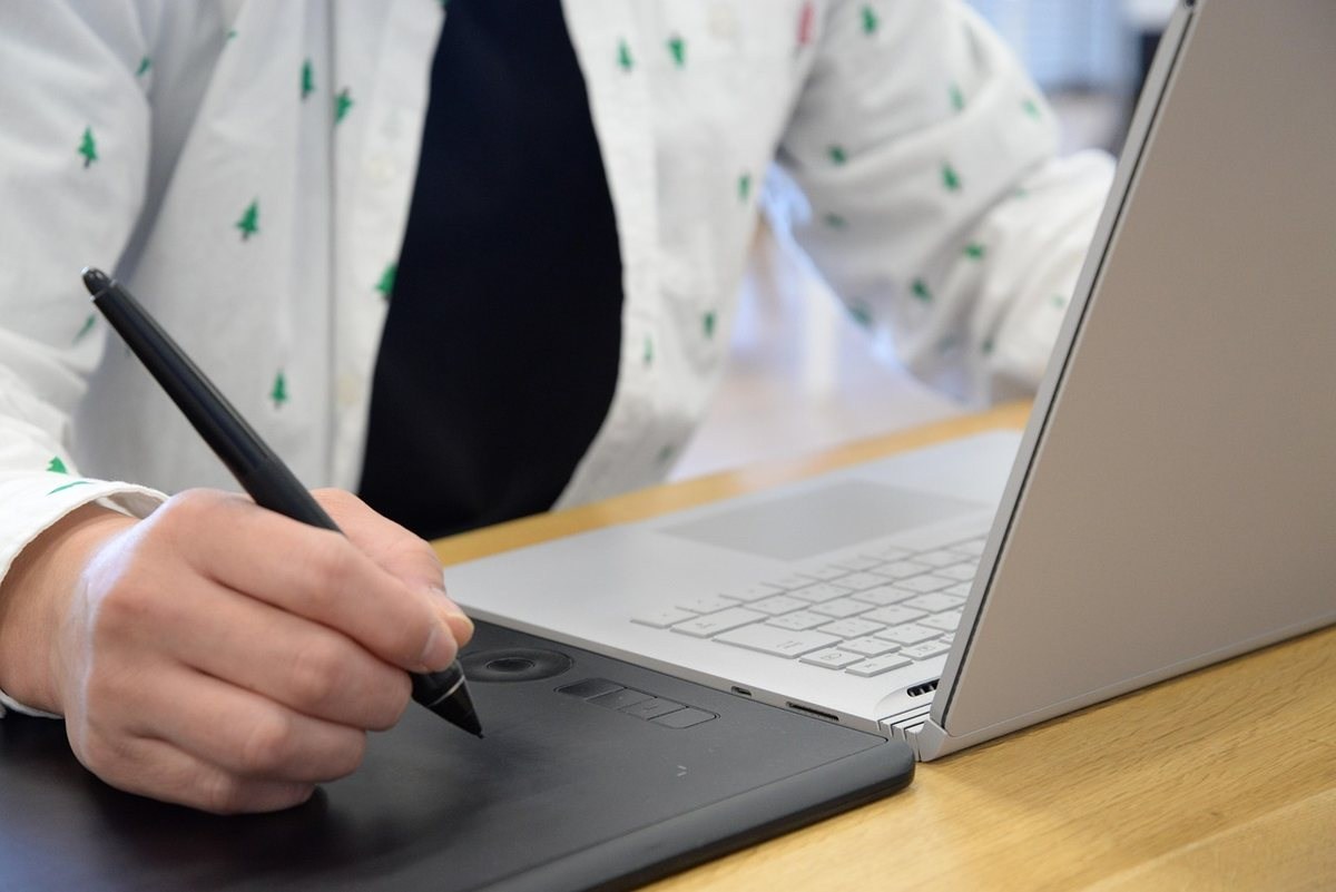 Personne tenant un stylet et dessinant sur une tablette graphique portable en position assise